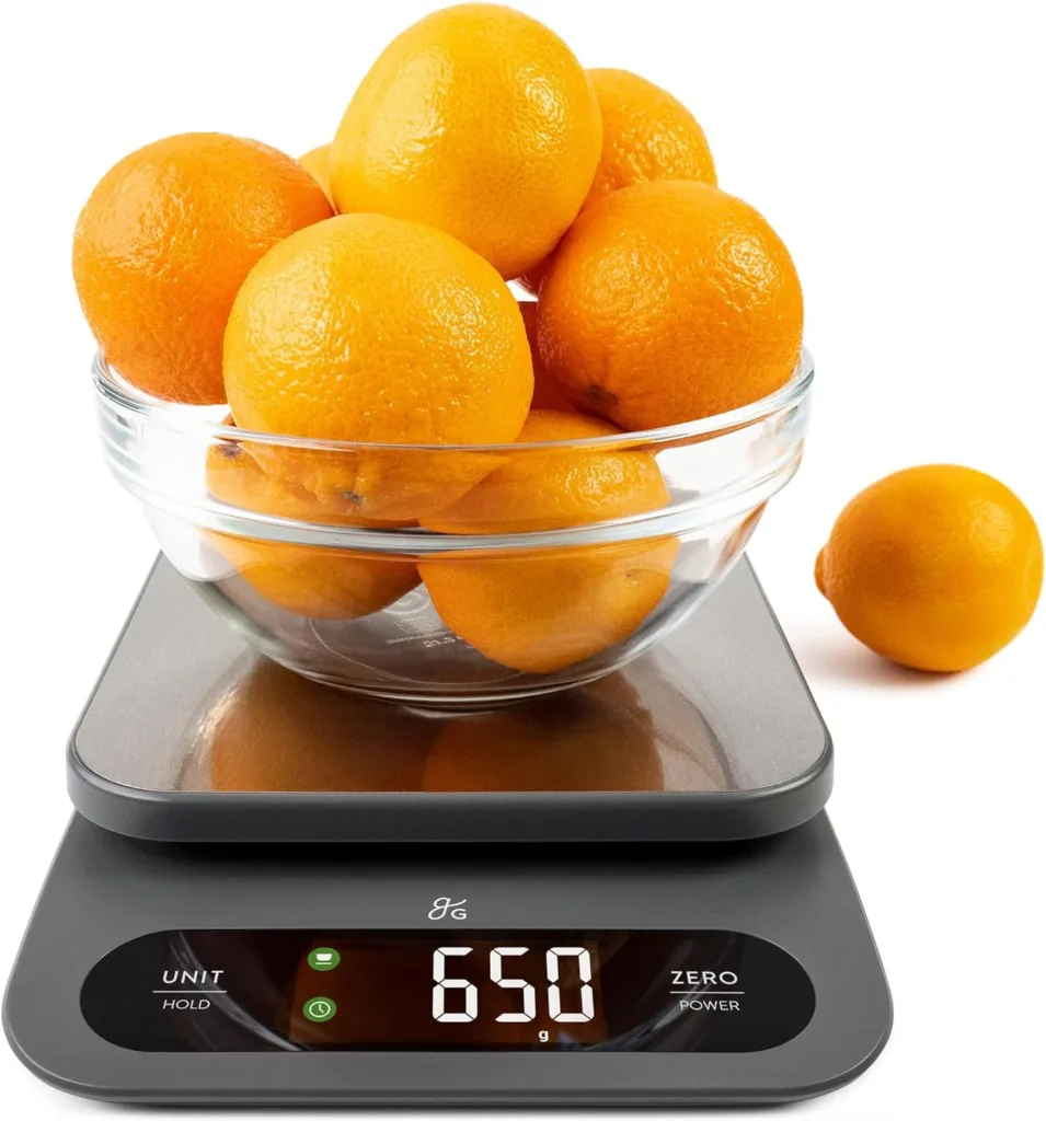 Digital kitchen scale displaying 650g, weighing a bowl of oranges. Keto-friendly recipe ingredient.