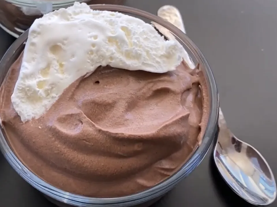 Close-up of creamy chocolate mousse topped with whipped cream; a simple keto dessert.