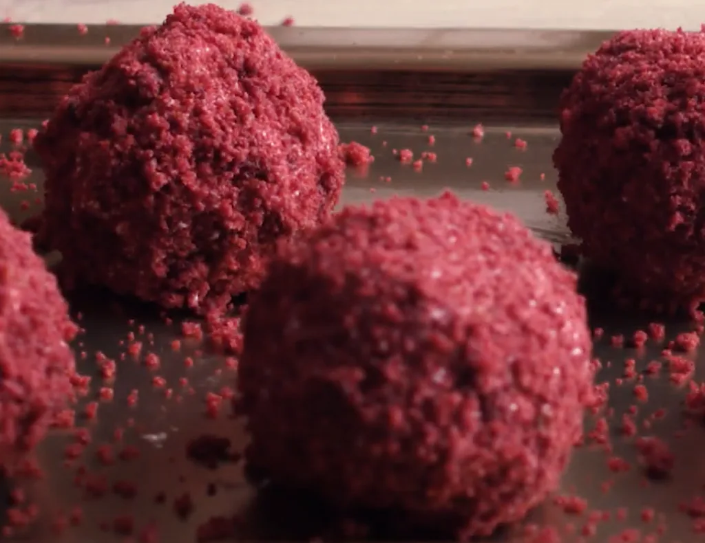 Close-up of four delicious keto raspberry dessert balls coated in crushed nuts.