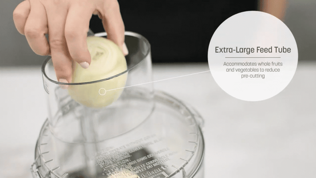 Hand placing onion in Cuisinart 14-cup food processor's extra-large feed tube.
