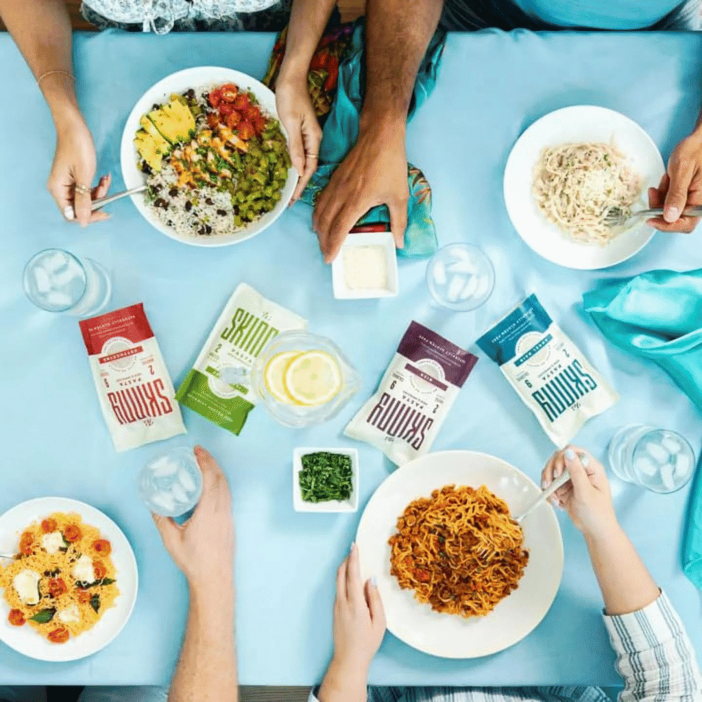 Overhead view of four people enjoying various It's Skinny Pasta dishes.